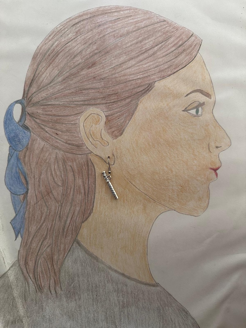Peut inclure: Un dessin d'une personne aux cheveux bruns portant une boucle d'oreille en argent avec un design d&eacute;taill&eacute;. La boucle d'oreille est en forme de baguette.