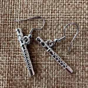 Peut inclure: Une paire de boucles d'oreilles en argent en forme de fl&ucirc;tes. Les boucles d'oreilles ont un design d&eacute;taill&eacute; et sont suspendues &agrave; des crochets en argent.