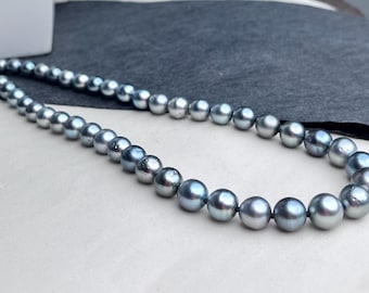 May include: A single strand necklace featuring a series of round, lustrous dark grey pearls. The pearls are uniform in shape and size, strung together in a continuous line, displaying a metallic sheen and smooth surface texture throughout the piece.