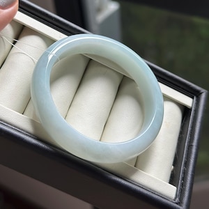 Pode incluir: Uma pulseira tipo bracelete de jade verde menta p&aacute;lido, lisa e polida, com uma apar&ecirc;ncia transl&uacute;cida e um perfil arredondado. A pe&ccedil;a de joalharia circular apresenta varia&ccedil;&otilde;es subtis na intensidade da cor e um acabamento brilhante.