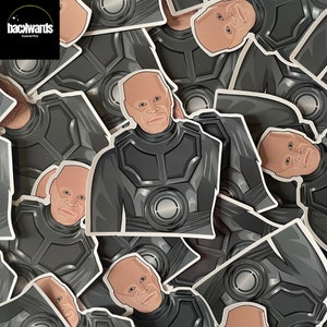 May include: A collection of black and grey stickers featuring a bald man with a serious expression wearing a futuristic suit. The stickers are arranged in a random pattern and have a glossy finish.