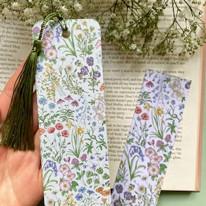 Op de afbeelding: Twee bloemen-bladwijzers met een groene kwast. De bladwijzers hebben een witte achtergrond met een verscheidenheid aan kleurrijke bloemen en groen.