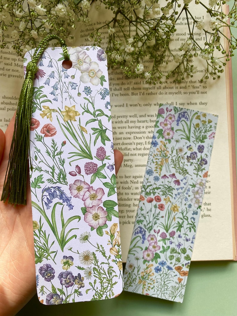 Op de afbeelding: Twee bloemen-bladwijzers met een witte achtergrond en een verscheidenheid aan kleurrijke bloemen, waaronder blauwe bellen, viooltjes en rozen.
