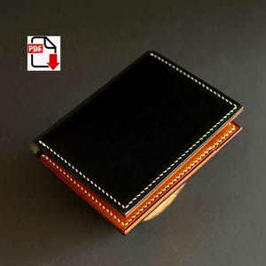 May include: A black leather wallet with white stitching around the edges. The interior is a lighter brown colour. The wallet is closed and appears to be new.