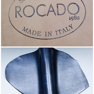 May include: A tan leather surface with the text "SHELL CORDOVAN ROCADO 1982 MADE IN ITALY" in black. Below is a blue leather piece with the word "Blue" in the bottom right corner.