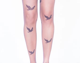 May include: Sheer pantyhose with a repeating pattern of dark gray bird silhouettes. The legs are shown from the knees down, with black high-heeled shoes. The background is white.