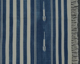 May include: A blue and white striped rug with a fringe border. The rug has a subtle pattern of white arrows on the blue stripes.
