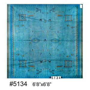 Op de afbeelding: Een blauw tapijt met een geometrisch patroon in tinten oranje, zwart en wit. Het tapijt is 2,03 m x 2,03 m.