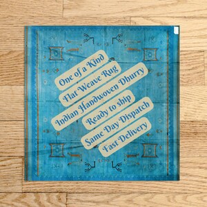 Op de afbeelding: Een handgeweven tapijt in blauw en wit met de tekst "One of a Kind", "Flat Weave Rug", "Indian Handwoven Dhurry", "Ready to ship", "Same Day Dispatch" en "Fast Delivery".