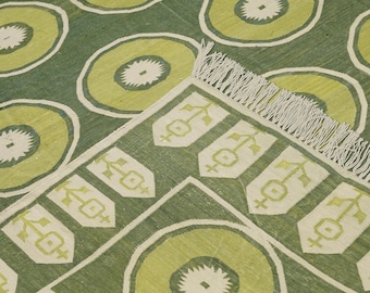 May include: Green and cream patterned rug with a geometric design. The rug has a fringed border.