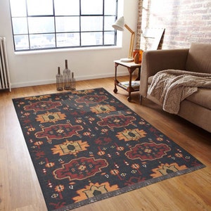 May include: A black and red patterned rug with a geometric design. The rug has a fringe border and is laid out on a wooden floor in a living room setting.