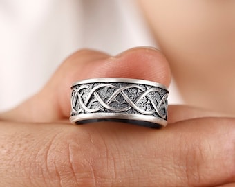 May include: A silver ring with a Celtic knot design. The ring is wide and has a textured finish.