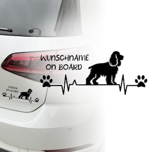 Op de afbeelding: Zwart-witte auto sticker met een silhouet van een cocker spaniel, een hartslag en voetafdrukken. De tekst "Wunschname on Board" staat boven het silhouet van de hond.