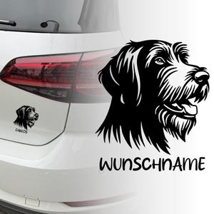 Puede incluir: Calcomanía de perro en blanco y negro con el texto "WUNSCHNAME". También es visible una versión más pequeña de la calcomanía del perro con el nombre "CARLOS". Las calcomanías están aplicadas a un coche blanco.