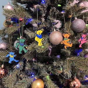 May include: A decorated Christmas tree with colorful ornaments and dancing bear ornaments. The tree is adorned with various round ornaments in gold, silver, and bronze. The dancing bear ornaments are in blue, green, yellow, orange, and pink.