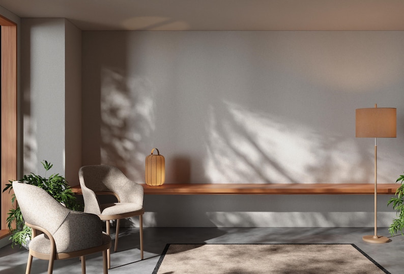 May include: Two beige chairs with wooden legs and a wooden shelf with a small wooden lamp on it. The wall is white with shadows from a window. There is a rug on the floor.