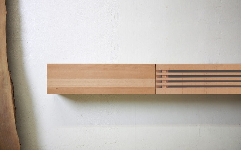 May include: A wooden shelf with a decorative slatted panel on the right side. The shelf is made of light wood and is mounted on a white wall.