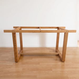 K&ouml;nnte beinhalten: Hellbraunes Holz-Tischgestell mit rechteckiger Oberseite und abgewinkelten Beinen. Das Tischgestell ist aus Massivholz gefertigt und hat ein schlichtes, modernes Design. Das Tischgestell ist ca. 152 cm lang und 76 cm breit.