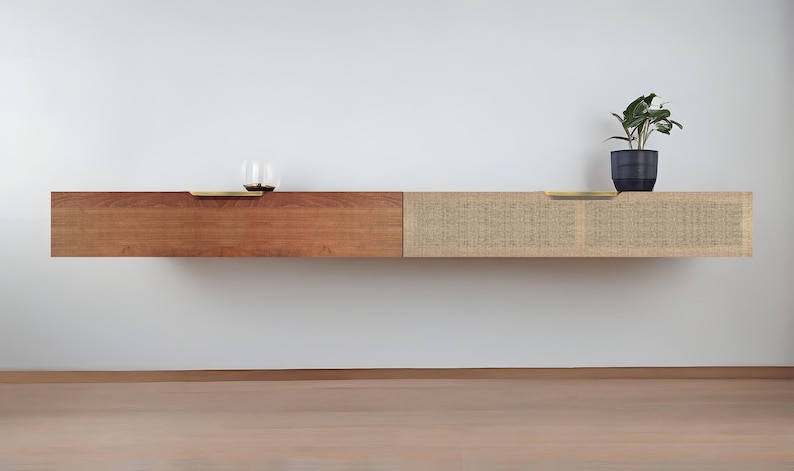 May include: A floating wall shelf with two sections. The left section is made of dark wood and the right section is made of woven natural fiber. Both sections have brass pulls.