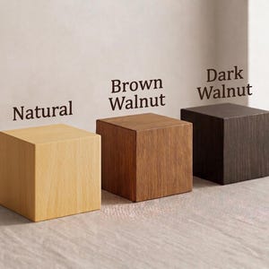 Op de afbeelding: Drie houten kubussen in natuurlijke, bruine walnoot en donkere walnoot afwerkingen. Elke kubus is een solide vierkante vorm, met de namen van de kleuren erboven afgedrukt. De kubussen worden op een lichtgekleurd oppervlak weergegeven.