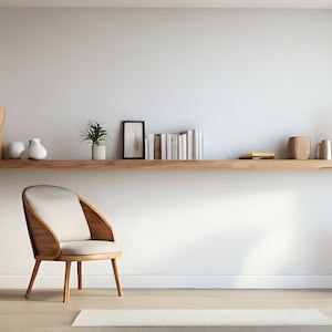 Puede incluir: Una estantería de madera clara con una variedad de artículos decorativos, incluyendo un jarrón, una planta y libros. Una silla blanca con un marco de madera clara se encuentra frente a la estantería. Una pequeña mesa auxiliar de madera con una taza y un platillo blancos se encuentra en la esquina de la habitación.