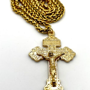 Puede incluir: Un collar de cadena de oro con un colgante de crucifijo de oro. El crucifijo presenta un diseño detallado con una figura de Jesucristo.