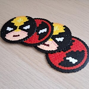 May include: Four round coasters made of colourful perler beads, featuring a pixelated image of Deadpool's face.