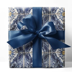May include: A wrapped gift box with a blue and white tile pattern, tied with a navy blue satin ribbon and bow. The box is rectangular and the ribbon is wrapped around it horizontally and vertically.
