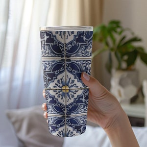 May include: A stainless steel tumbler with a blue and white tile pattern. The tile pattern features a repeating design of blue and white floral motifs.