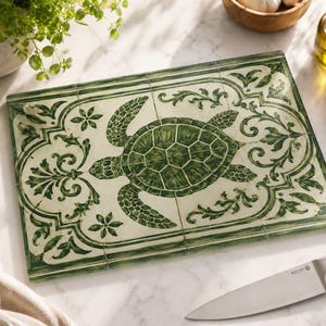 May include: A rectangular glass chopping board featuring a central green sea turtle illustration surrounded by an intricate green and white scrollwork border. The design mimics the appearance of four square tiles joined together with visible grout lines.