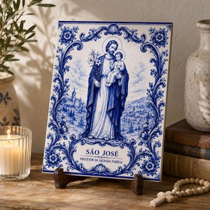 Può includere: Una piastrella rettangolare in ceramica con un'illustrazione blu e bianca di San Giuseppe che tiene in braccio Gesù bambino. Il design include un bordo floreale decorato e il testo "SÃO JOSÉ PROTETOR DA SAGRADA FAMÍLIA" in basso.