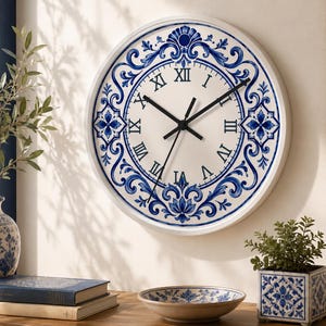 May include: White wall clock with a blue floral design and black hands. The clock has Roman numerals and is surrounded by a white frame. The clock is part of a collection of blue and white decorative items.