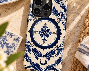 May include: A smartphone case featuring a cream-colored background with a dark blue intricate floral and scrollwork pattern. The design includes a central circular medallion with a stylized cross motif and a triple-lens camera cutout.
