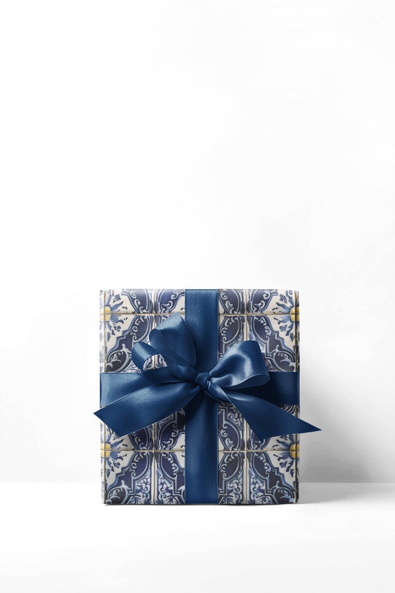 May include: A wrapped gift box with a blue and white tile pattern, tied with a navy blue satin ribbon and bow. The box is rectangular and the ribbon is wrapped around it horizontally and vertically.