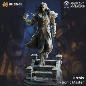 May include: A detailed miniature figurine of a male figure in a flowing robe and armor, holding a glowing orb in his hand. The figure is standing on a stone platform with a base. The figurine is painted in a gray color scheme. The text "Orthis Psionic Master" is printed below the figure.