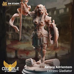 May include: A miniature figurine of a lioness gladiator, painted in a light brown color, holding a spear and shield. The figurine is standing on a circular base with a broken column behind it. The text "Aktara Adrientem Lioness Gladiator" is written below the figurine.