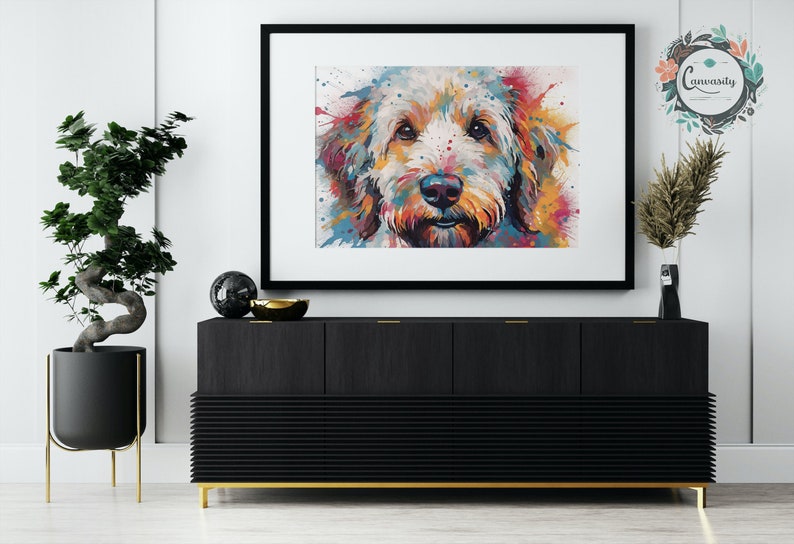May include: A colorful abstract painting of a dog's face. The dog is a light brown color with a white muzzle and black nose. The background is a white canvas with splashes of color in shades of blue, green, yellow, orange, and red.
