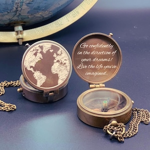 May include: Two antique brass compasses with a world map and inspirational quote. One compass is open, revealing the internal dial and the quote "Go confidently in the direction of your dreams! Live the life you've imagined."