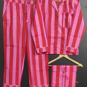 K&ouml;nnte beinhalten: Ein rot-wei&szlig; gestreiftes Pyjama-Set mit einem lang&auml;rmeligen Oberteil und einer Hose. Das Set hat einen Knopfleisten vorne und einen Kordelzug in der Taille.
