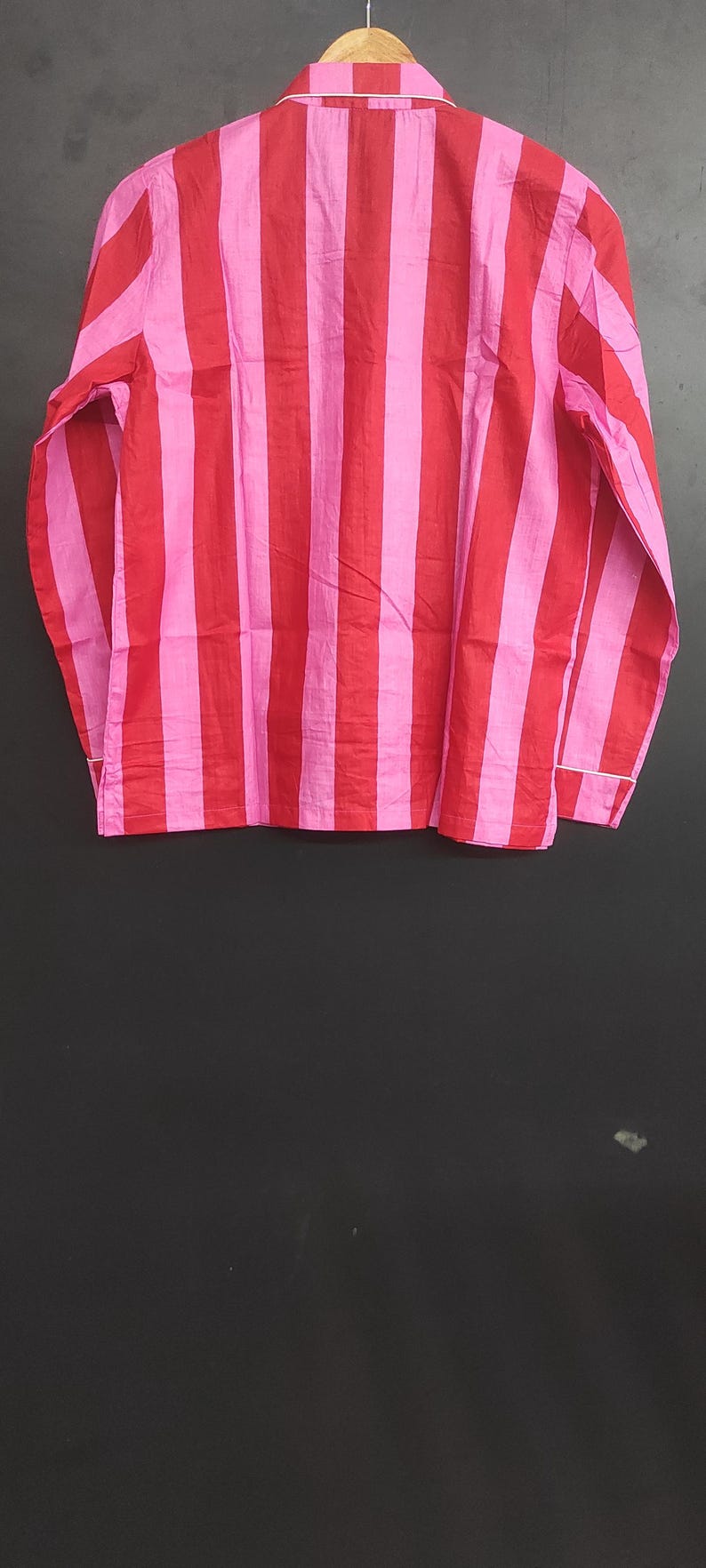 K&ouml;nnte beinhalten: Ein lang&auml;rmliges Hemd mit vertikalen rosa und roten Streifen. Das Hemd hat einen Knopfkrag und eine lockere Passform.