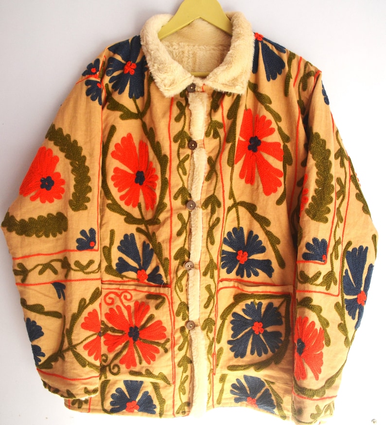 May include: A tan jacket with a brown faux fur collar and embroidered floral patterns in red, blue, and green.