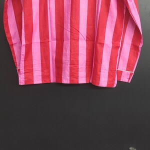 K&ouml;nnte beinhalten: Ein lang&auml;rmliges Hemd mit roten und pinkfarbenen Streifen und einem wei&szlig;en Kragen.