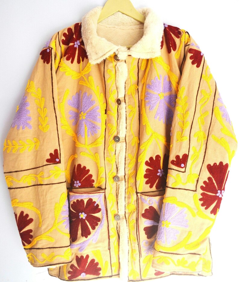 May include: A beige jacket with a faux fur collar and floral embroidery in shades of yellow, purple, and red.
