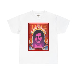 May include: A white short-sleeved t-shirt featuring a graphic print of a Time magazine cover titled The Jesus Revolution. The design displays a stylised portrait of a person with long hair and a beard in shades of purple, pink, and red.