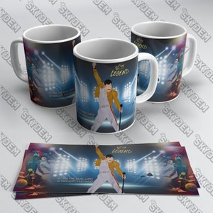 Puede incluir: Tazas de cerámica blanca con un diseño de actuación en el escenario. Las tazas muestran una silueta de un artista con una chaqueta amarilla y pantalones blancos, con la palabra "LEGEND" encima. También se ve el texto "IS THIS THE REAL LIFE? IS THIS JUST FANTASY?"