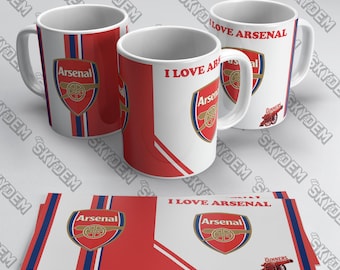 May include: White ceramic mugs with the Arsenal logo and the text "I LOVE ARSENAL". The mugs have red and blue accents. Also included are matching rectangular cards with the Arsenal logo and text.