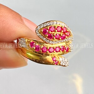 Puede incluir: Un anillo de oro con un diseño de espiral engastado con piedras rosas y blancas. El anillo es una pieza llamativa con un diseño único y atractivo.