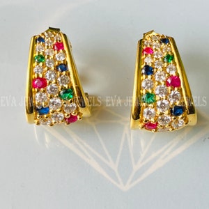 Puede incluir: Un par de pendientes de aro de oro con un diseño de piedras multicolores. Los pendientes están engastados con pequeñas piedras redondas en tonos de blanco, azul, verde y rojo.