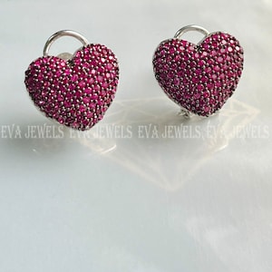 May include: A pair of silver heart-shaped earrings with pink cubic zirconia stones.