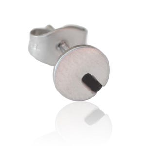 Könnte beinhalten: Ein silberner Ohrstecker mit einem runden Design mit einer Aussparung. Der Ohrring hat einen Stift und einen Schmetterlingsverschluss.